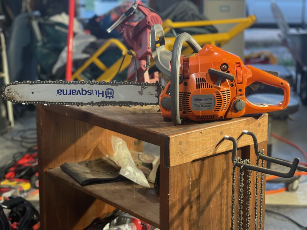 Husqvarna 450 Rancher 20" Chainsaw sitting on a sharpening bench with extra chains